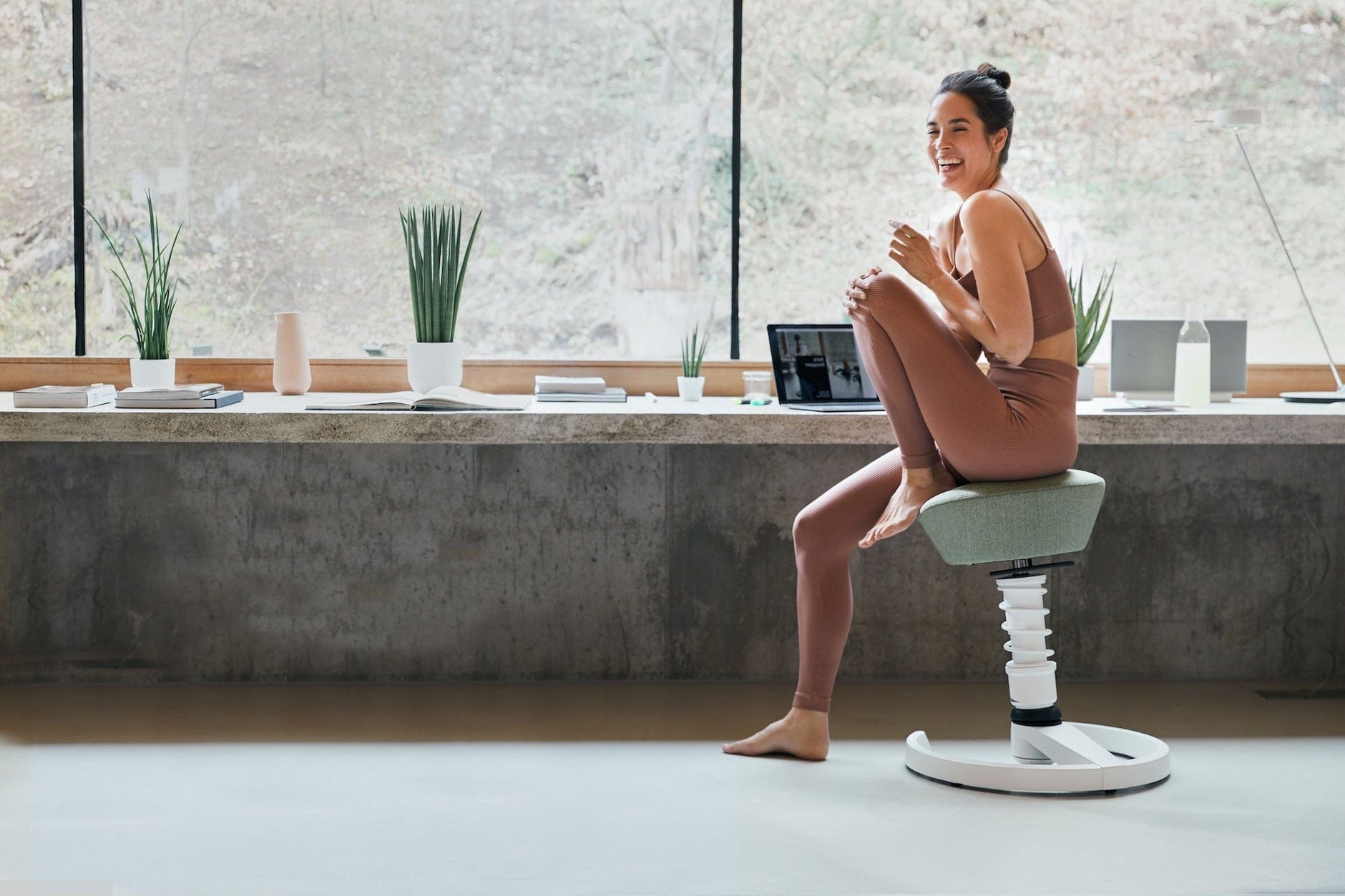 Frau sitzt in Sportkleidung im Home Office auf Aeris Swopper